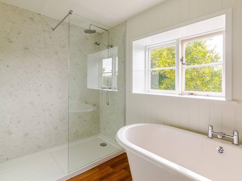 A bathroom with a shower and bathtub at Furzen Farmhouse