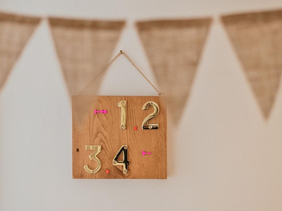 A wooden board with numbers hanging on the wall at Furzen Farmhouse