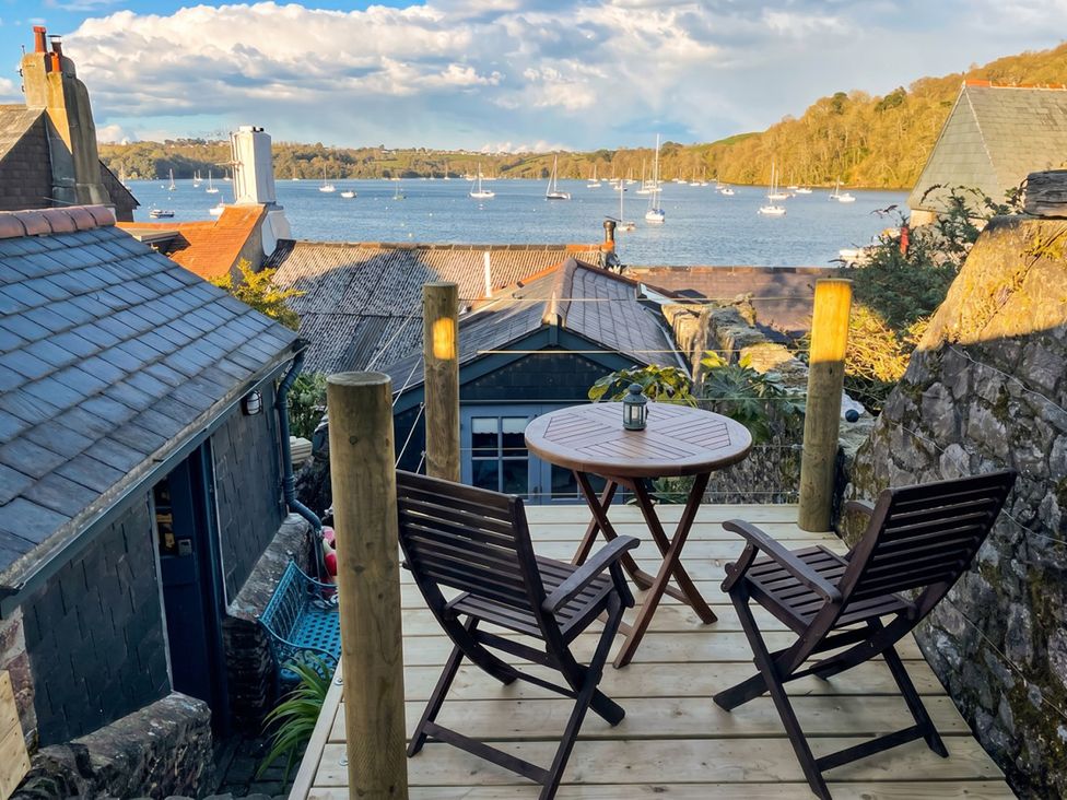 A balcony with two chairs and a table overlooking the sea at Quay Cottage