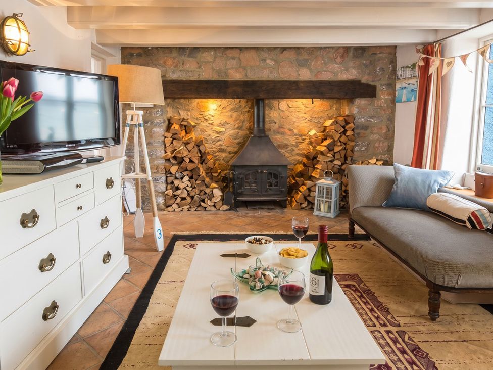 A living room with a fireplace and snacks on a table at Quay Cottage