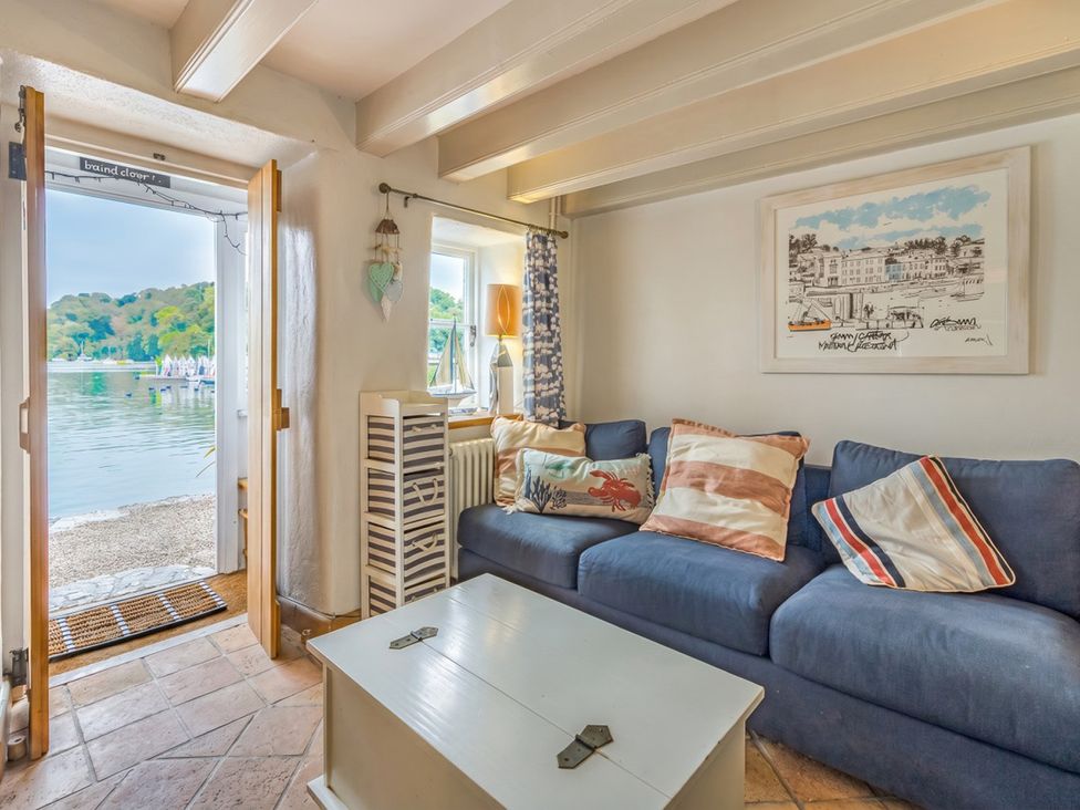 A living room with a sofa and window overlooking the water at Quay Cottage