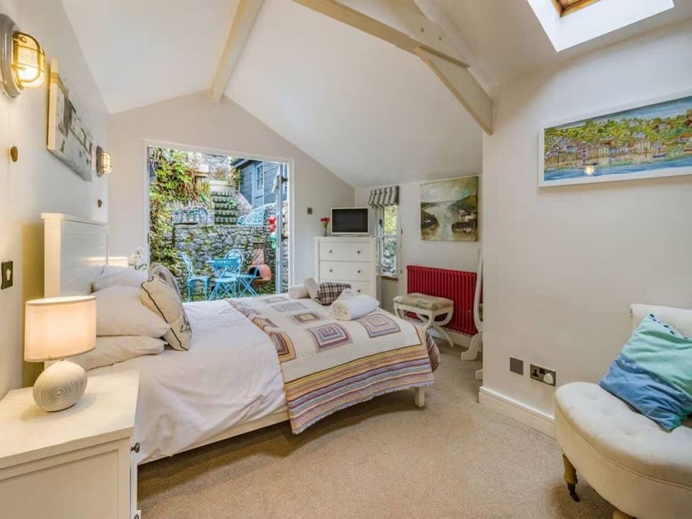 A bedroom with a bed and a view of the garden at Quay Cottage