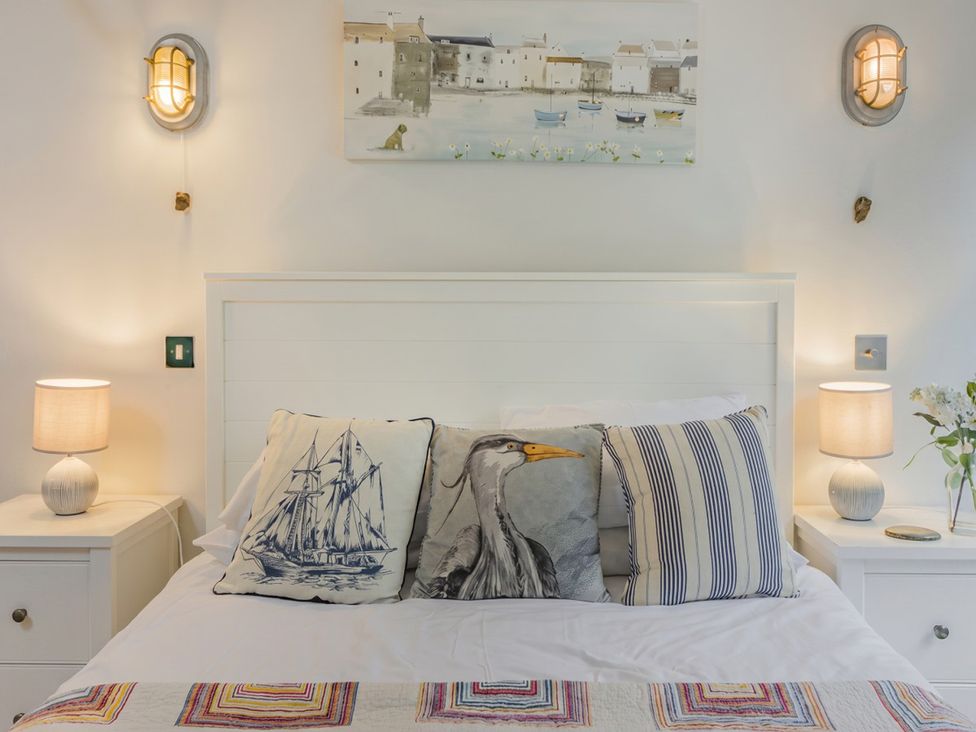 A bedroom with a bed and bedside lamps at Quay Cottage