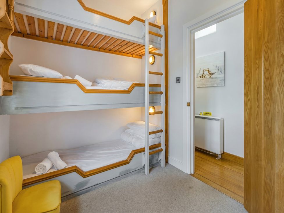 A bedroom with a bunk bed and chair at Quay Cottage