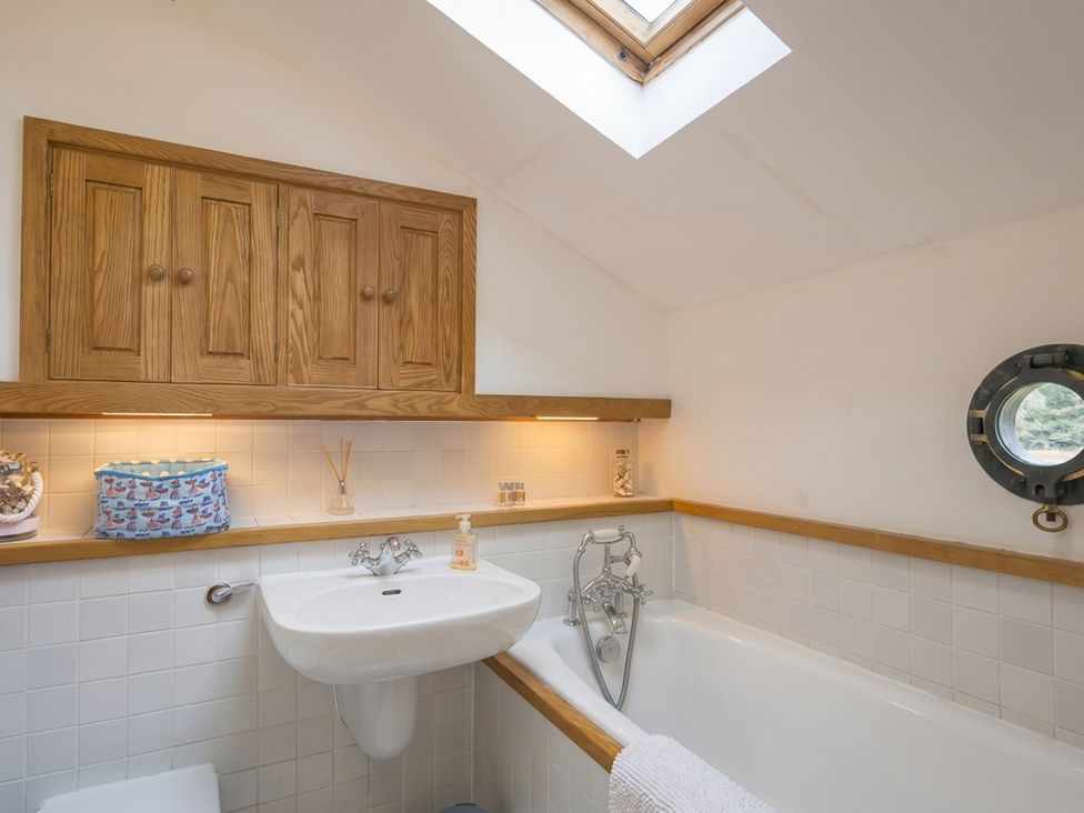 A bathroom with a sink and bath tub at Quay Cottage 