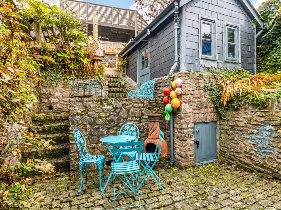 An outdoor area with a blue table and chairs against a stone wall at Quay Cottage
