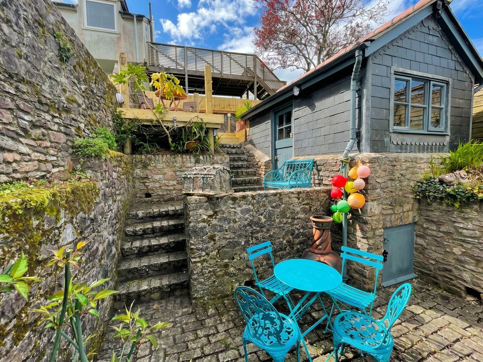 A garden with stairs leading to a small building and outdoor seating at Quay Cottage in 