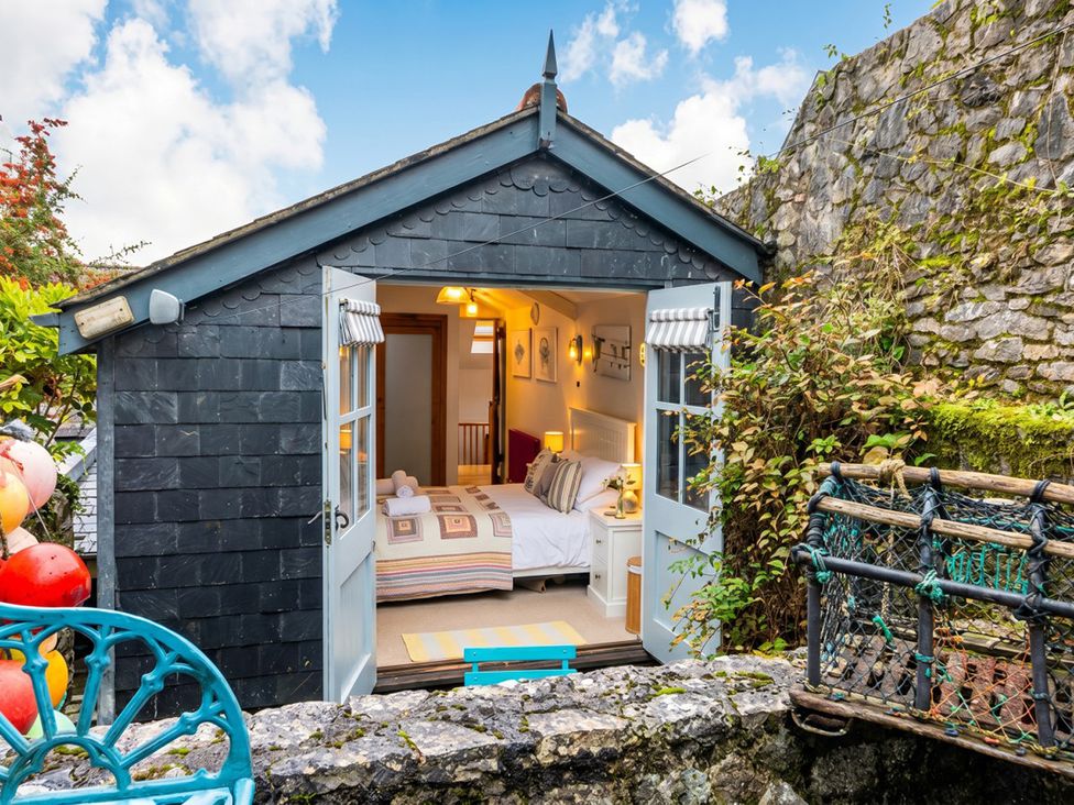 A bedroom with a double bed and windows at Quay Cottage 