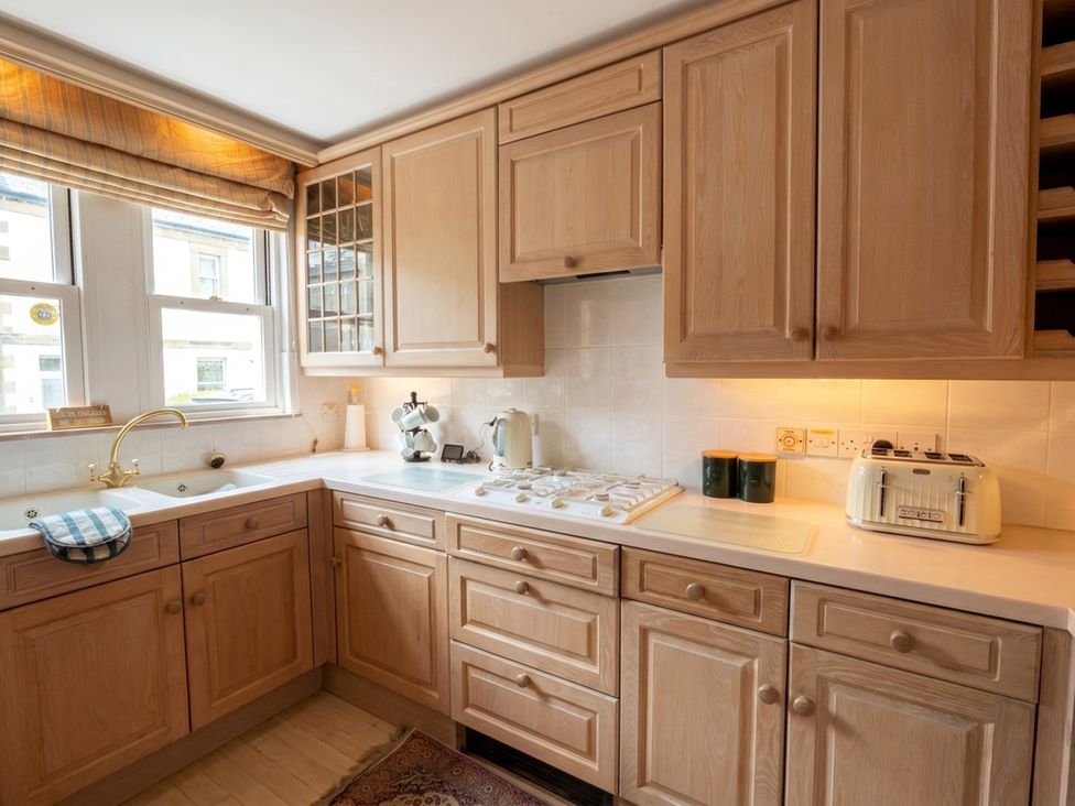 A kitchen with wooden cabinets and appliances at Circus Mews Townhouse