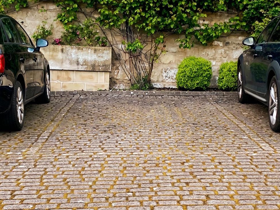 Two cars parked on cobblestone in a parking area with greenery at Circus Mews Townhouse