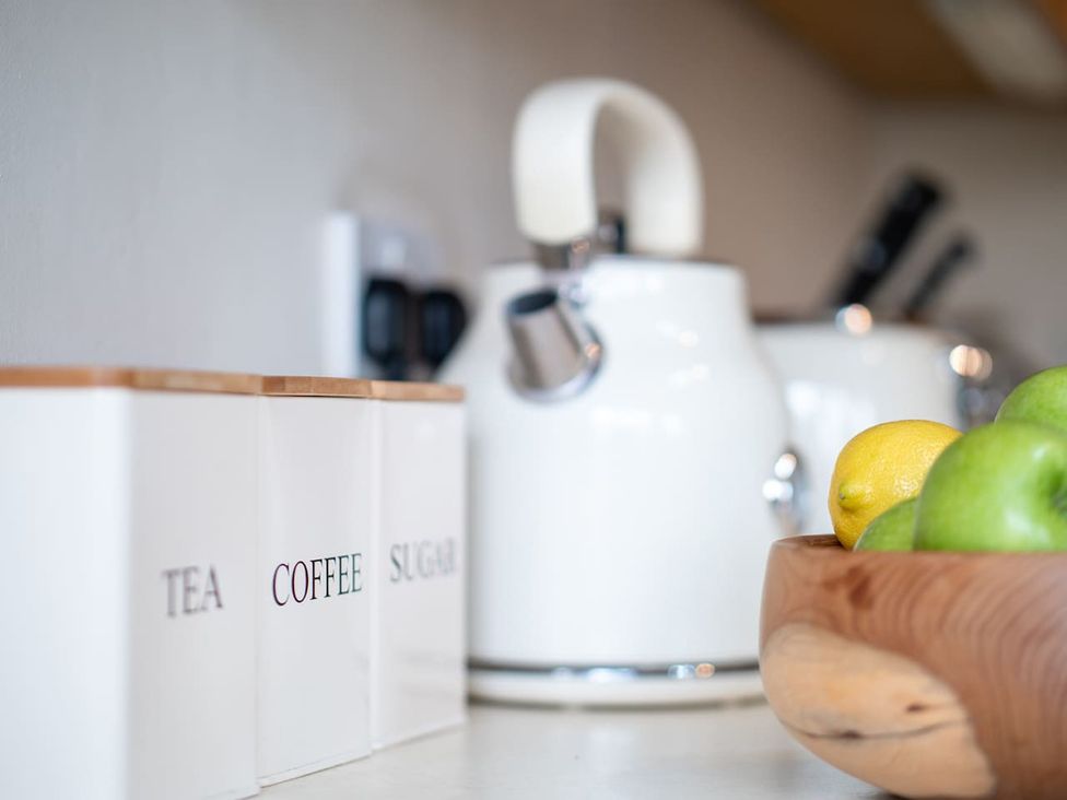 A kitchen with a kettle and containers for tea, coffee, and sugar at 