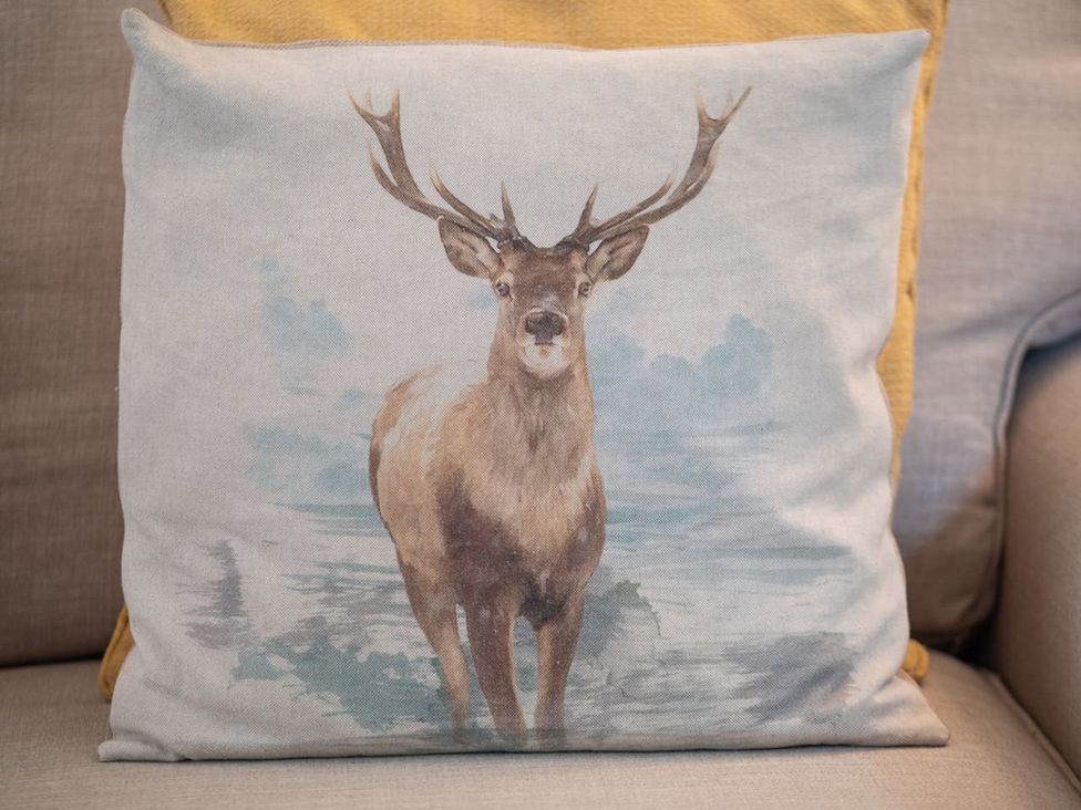 A cushion with a deer illustration in a living room at 