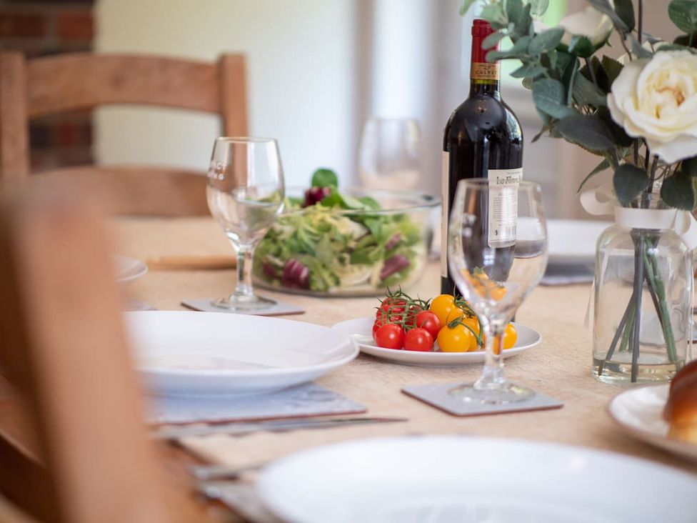 A dining room table set with plates, wine, and salad at the property in 