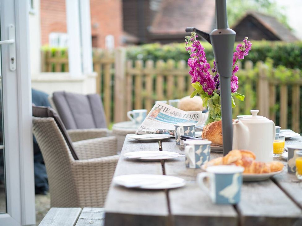 An outdoor dining area with a table set for breakfast with cups, a teapot, and a vase of flowers at 