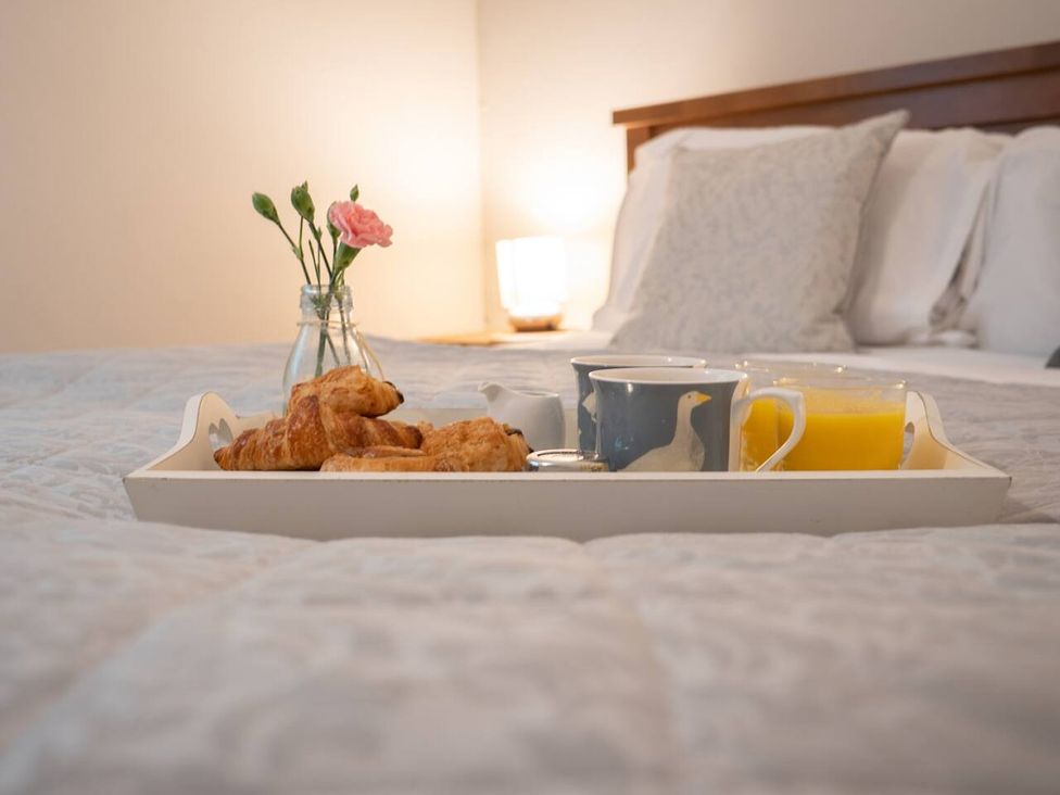 A tray with croissants, coffee, and orange juice on a bed at 
