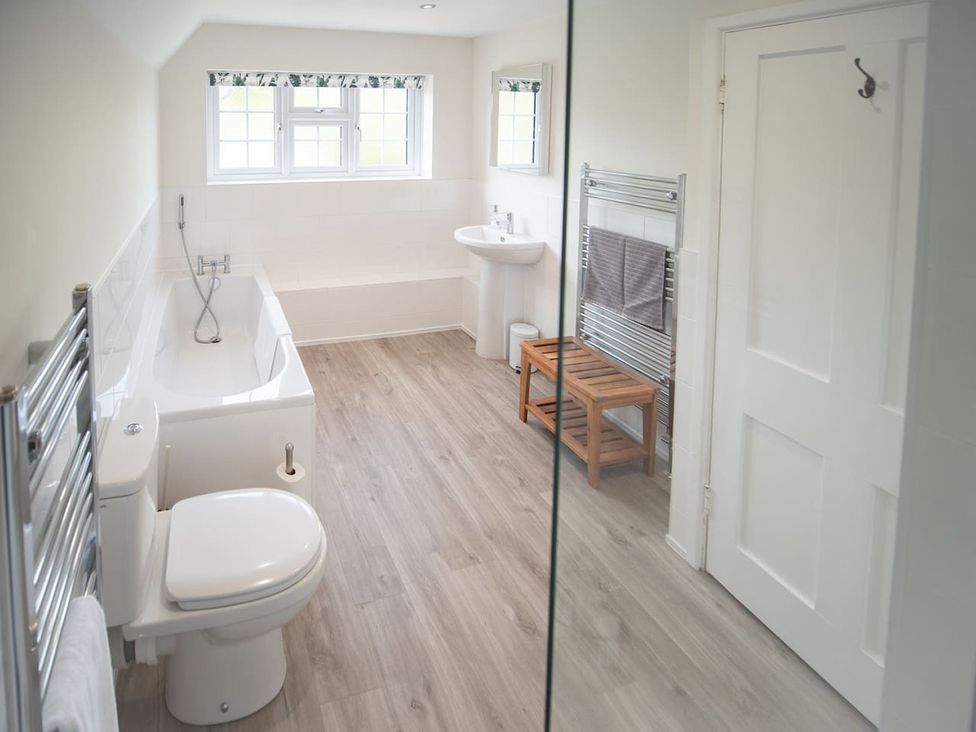 A bathroom with a bathtub, toilet, sink, and wooden stool at The Old Barn in Manchester