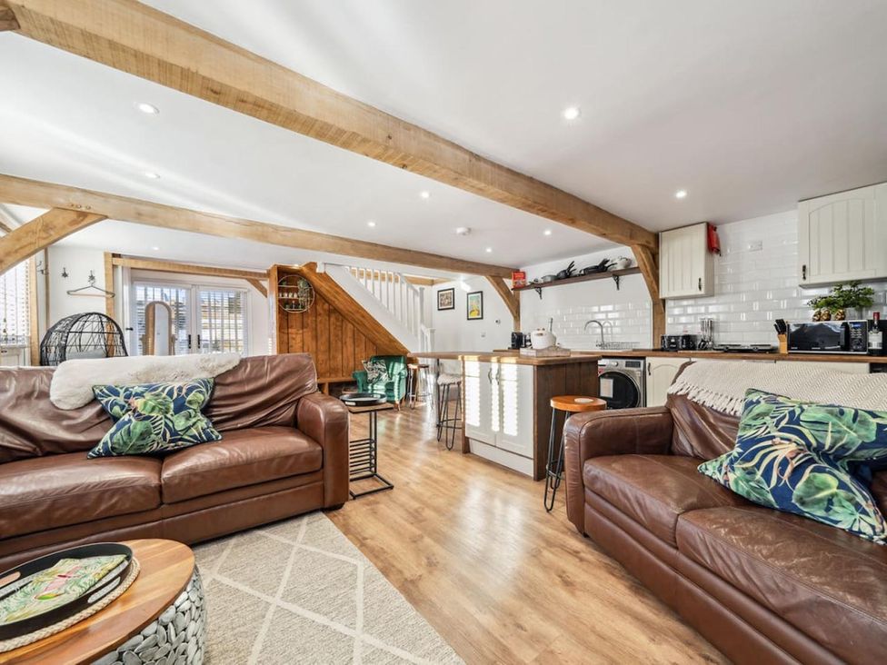 A living room with sofas and kitchen area at The Old Barn in Manchester