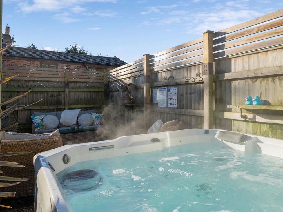 An outdoor area with a hot tub and seating at The Retreat in an unknown location