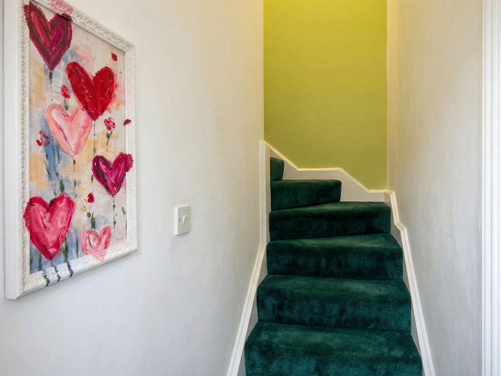A staircase with green carpet and a painting on the wall at the property