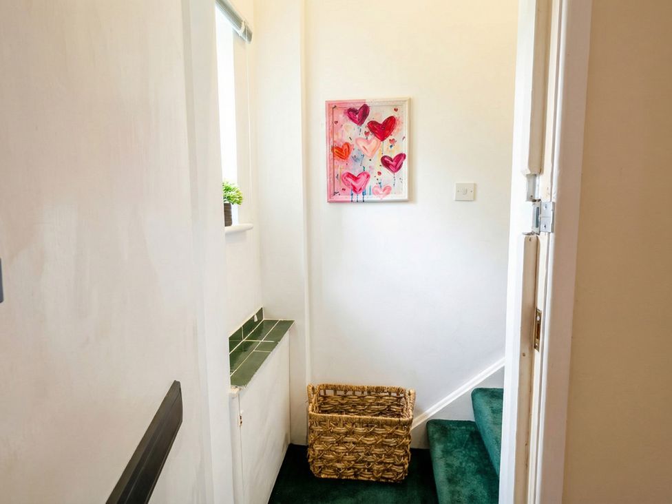 A hallway with a staircase and a basket at The Old Barn in Manchester