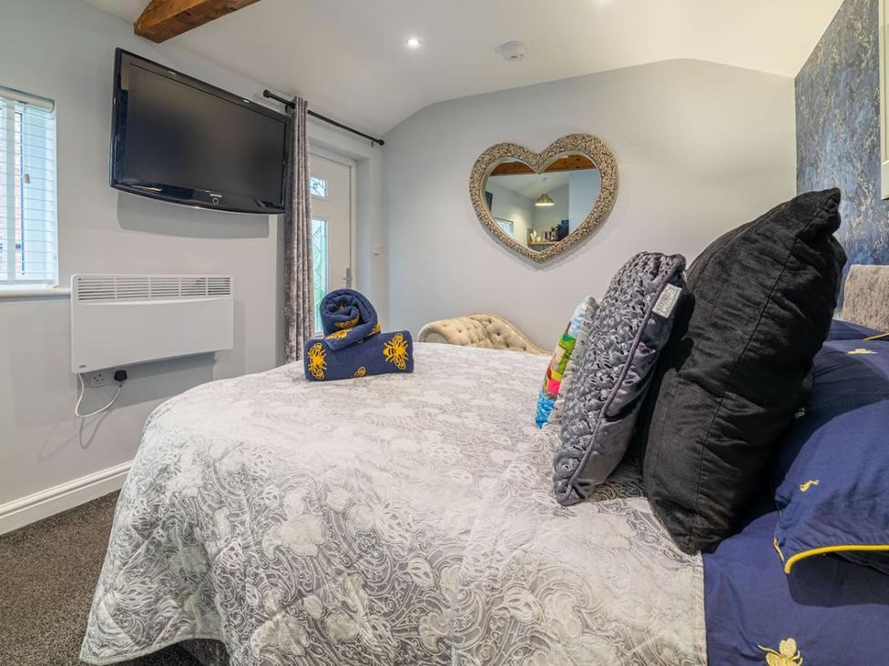A bedroom with a bed, television, and mirror at The Old Barn in Manchester