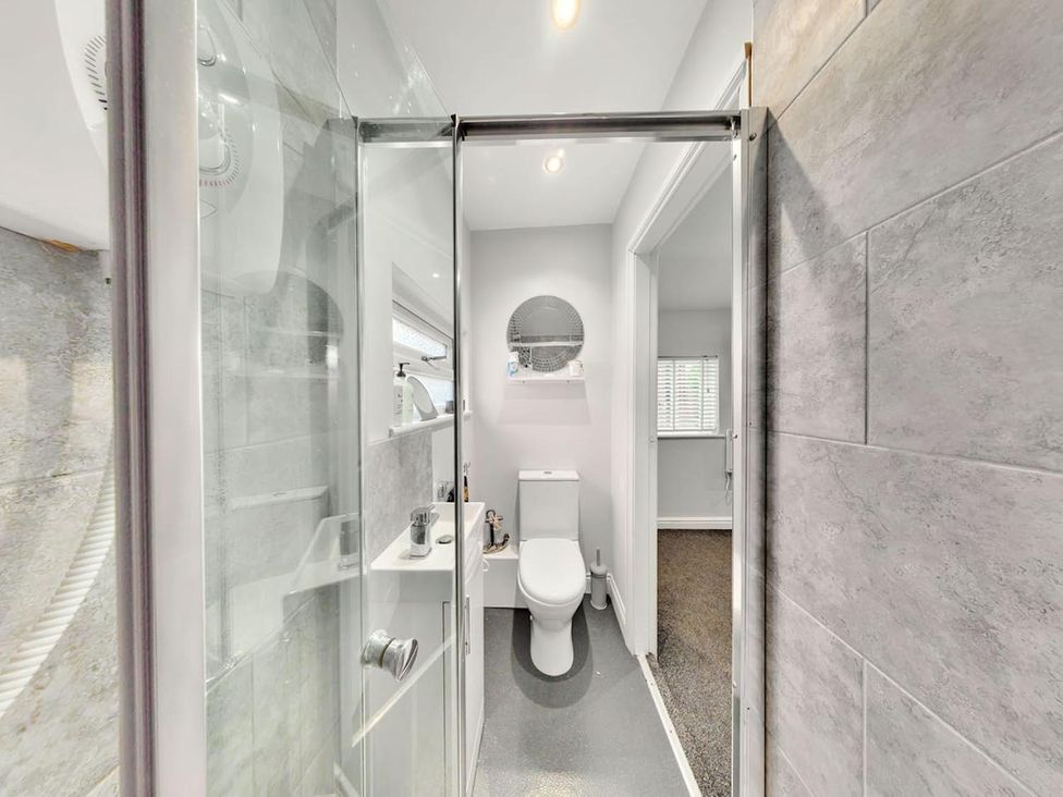 A bathroom featuring a shower, toilet, and sink with a mirror at the property in location