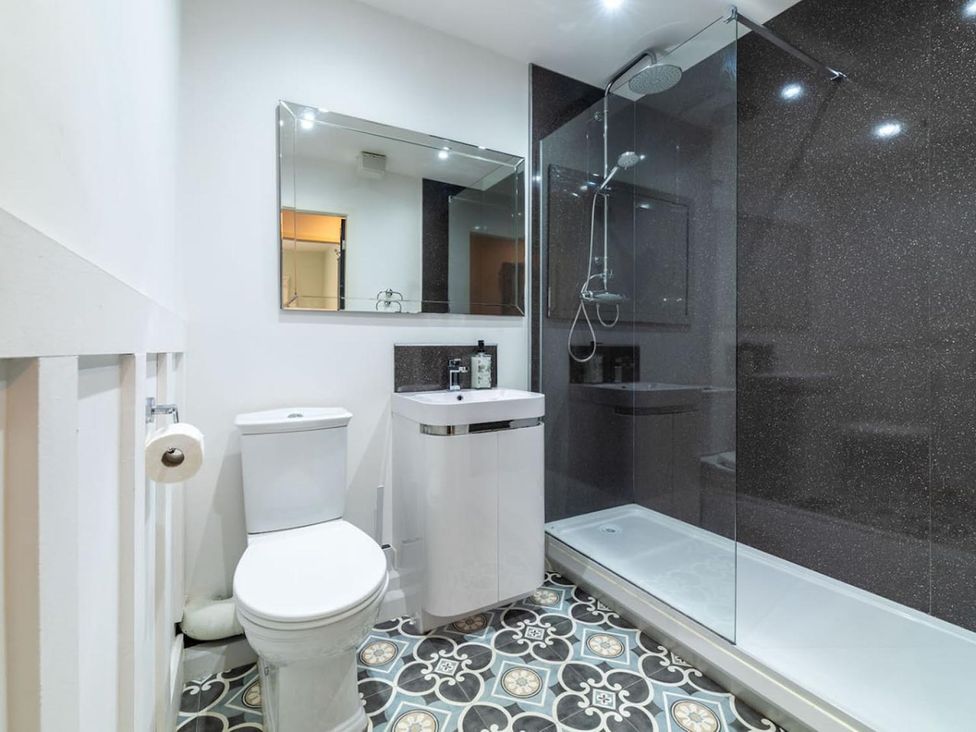 A bathroom with a toilet, sink, shower and mirror at The Old Barn in Manchester