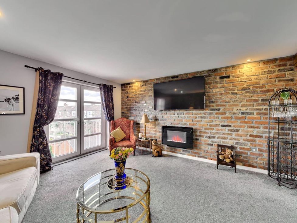 A living room with a rock wall and an electric fireplace at The Old Barn in Manchester