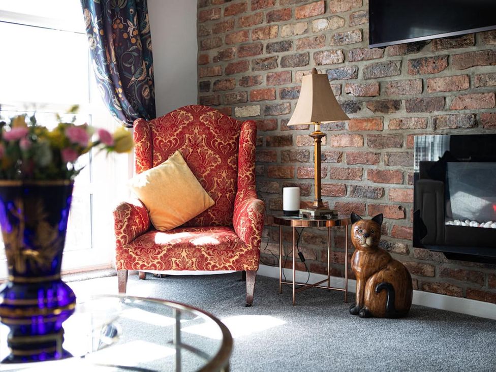 A living room with a red armchair and a brick wall at The Old Barn in Manchester