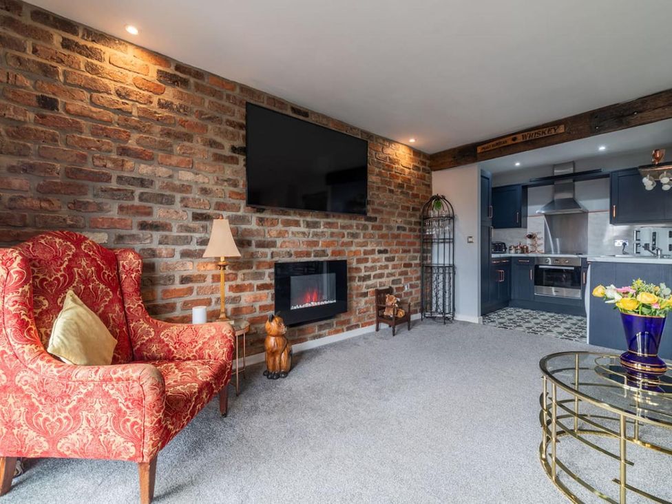 A living room with a brick wall and electric fireplace at the property