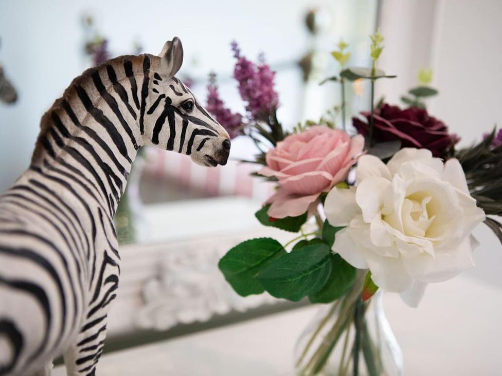 A zebra figurine beside a vase of artificial flowers in a decorative space