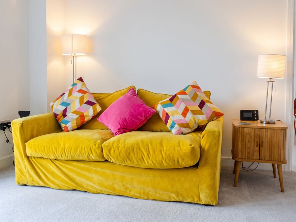A living room with a yellow sofa and side table at The Old Barn in Manchester