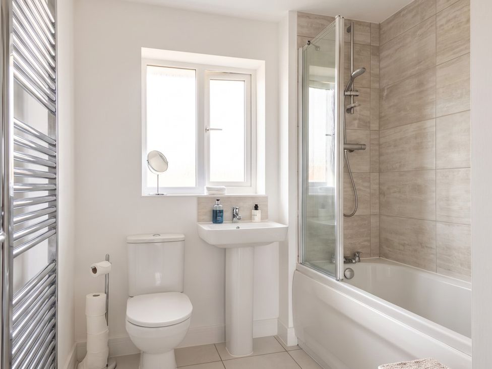 A bathroom featuring a toilet, sink, bathtub, and shower with natural light