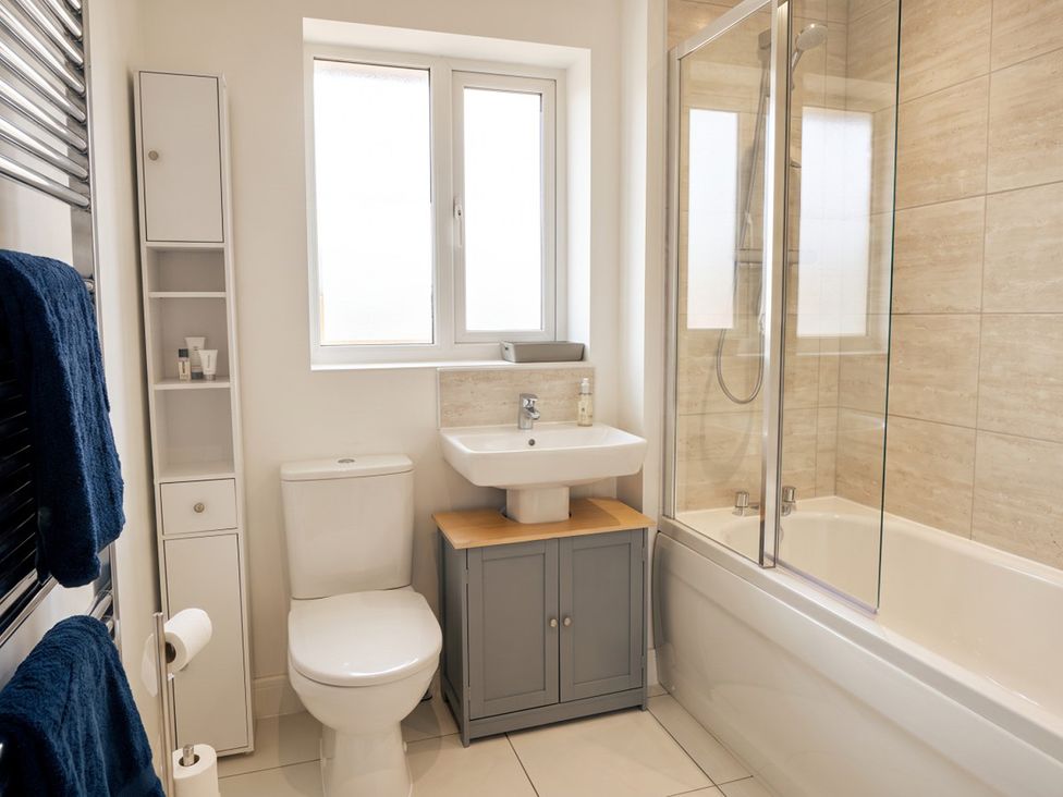 A bathroom with a toilet, sink, shower, and storage unit at 