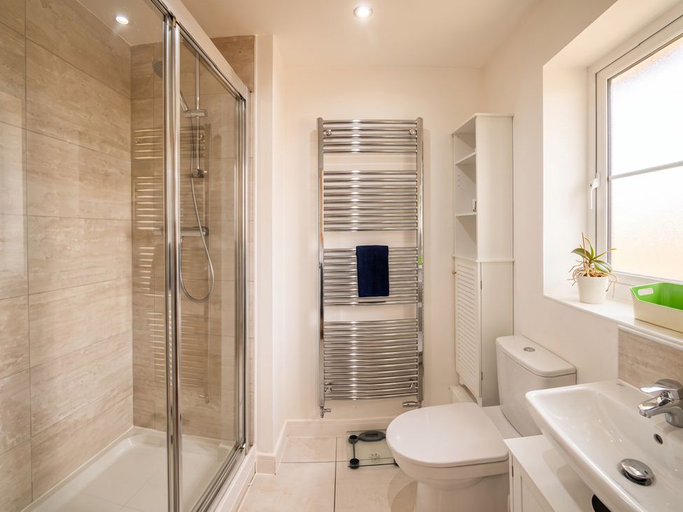 A bathroom with a shower, toilet, sink, and towel rail at The Old Barn in Manchester