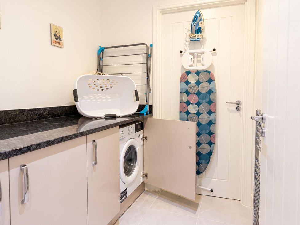 A laundry room featuring a washing machine, drying rack and iron at the property