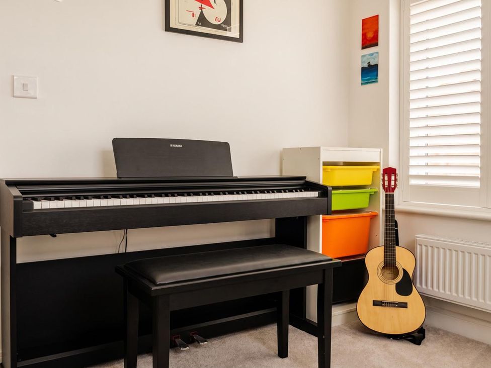 A music room with a piano a bench and a guitar