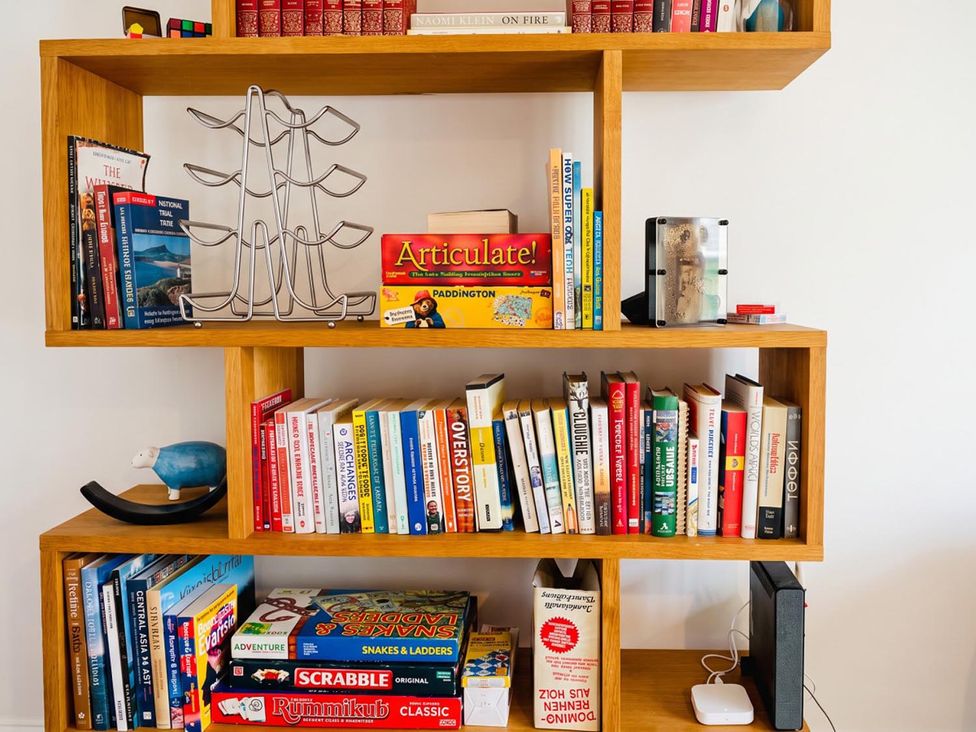 A bookshelf with assorted books and games at The Old Barn in Manchester