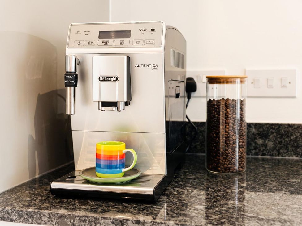 A coffee machine with a cup and coffee beans in a jar at The Old Barn in Manchester