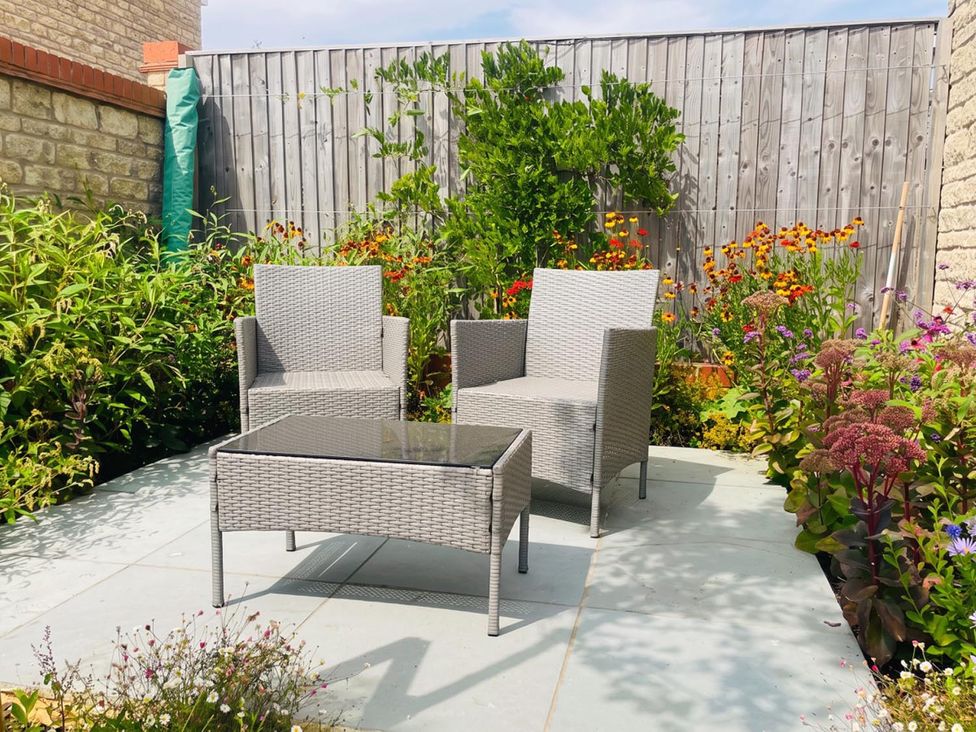 A garden with chairs and a table surrounded by flowers at the property