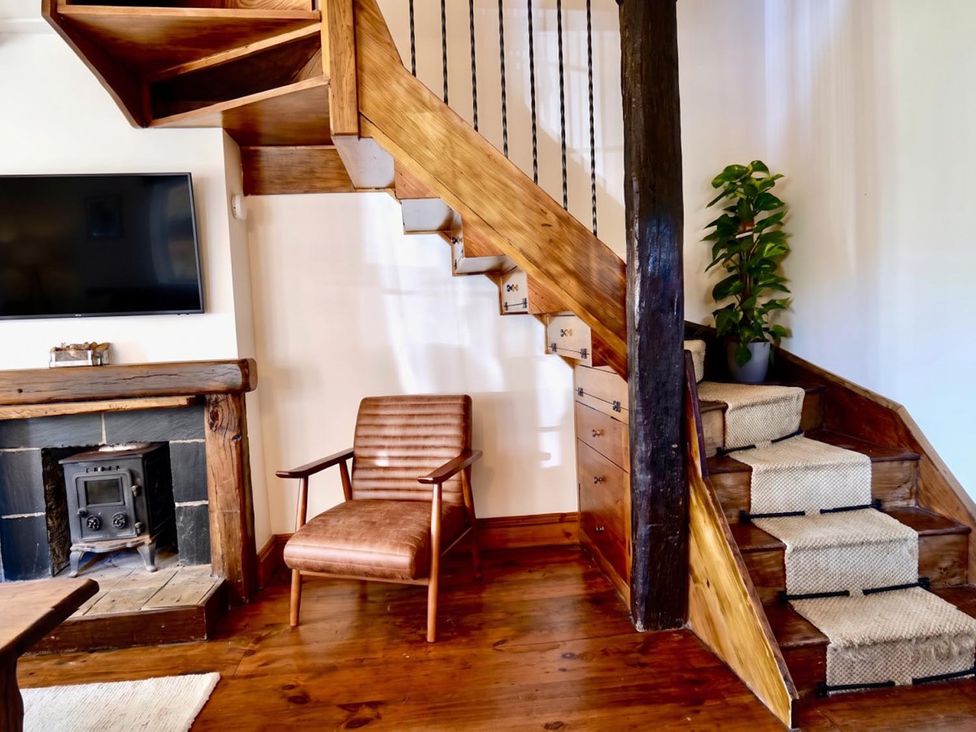 A living room with a staircase and TV at the property in the location