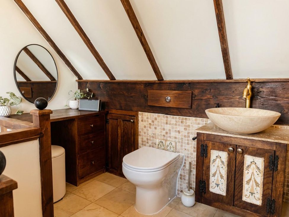 A bathroom with a toilet, sink, and mirror in an attic at the property