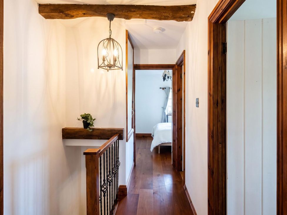 A hallway with a light fixture and wooden railing at The Old Barn in Manchester