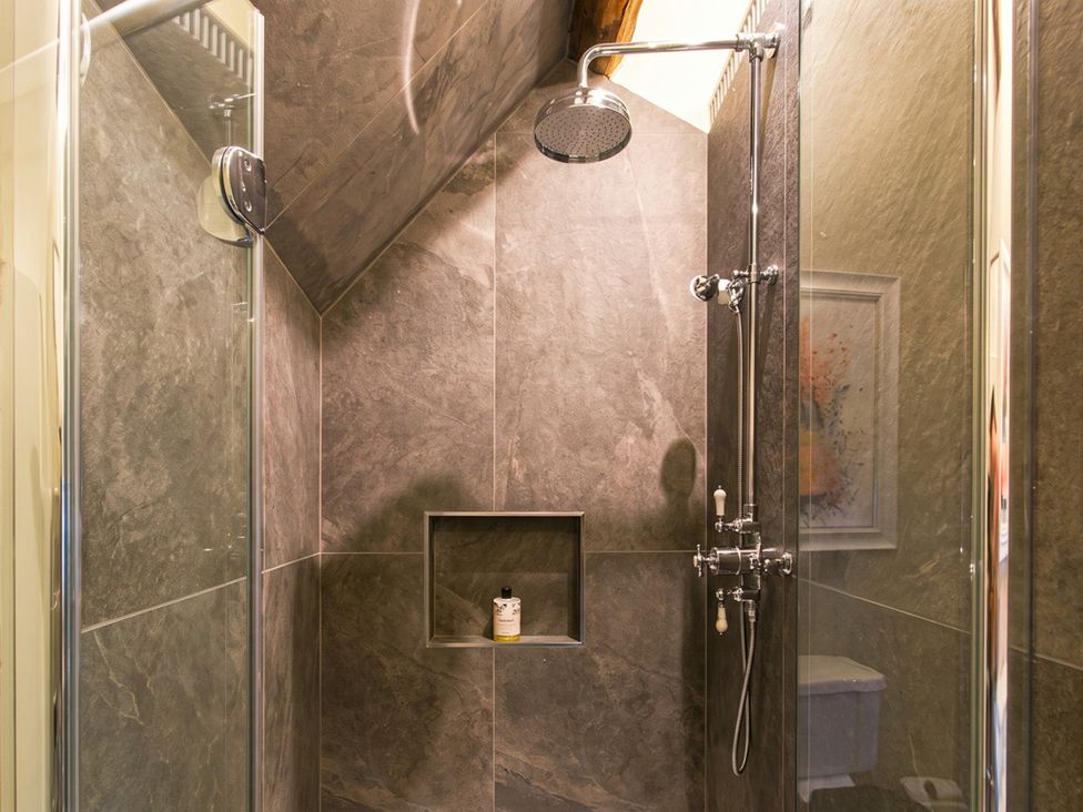 A shower with a shelf and a toilet in the bathroom