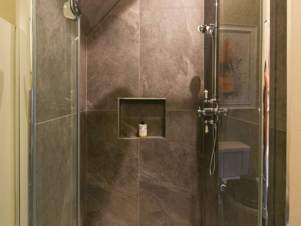 A shower with glass door and wall niche in a bathroom