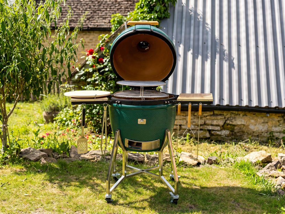 A green grill with work surfaces and tools in an outdoor area