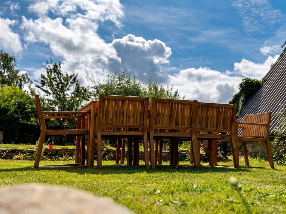 A wooden table with chairs in a garden with trees at 