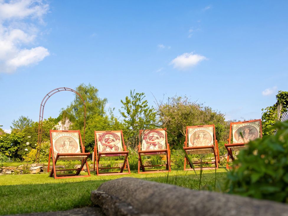 Deck chairs in a garden with trees and a blue sky