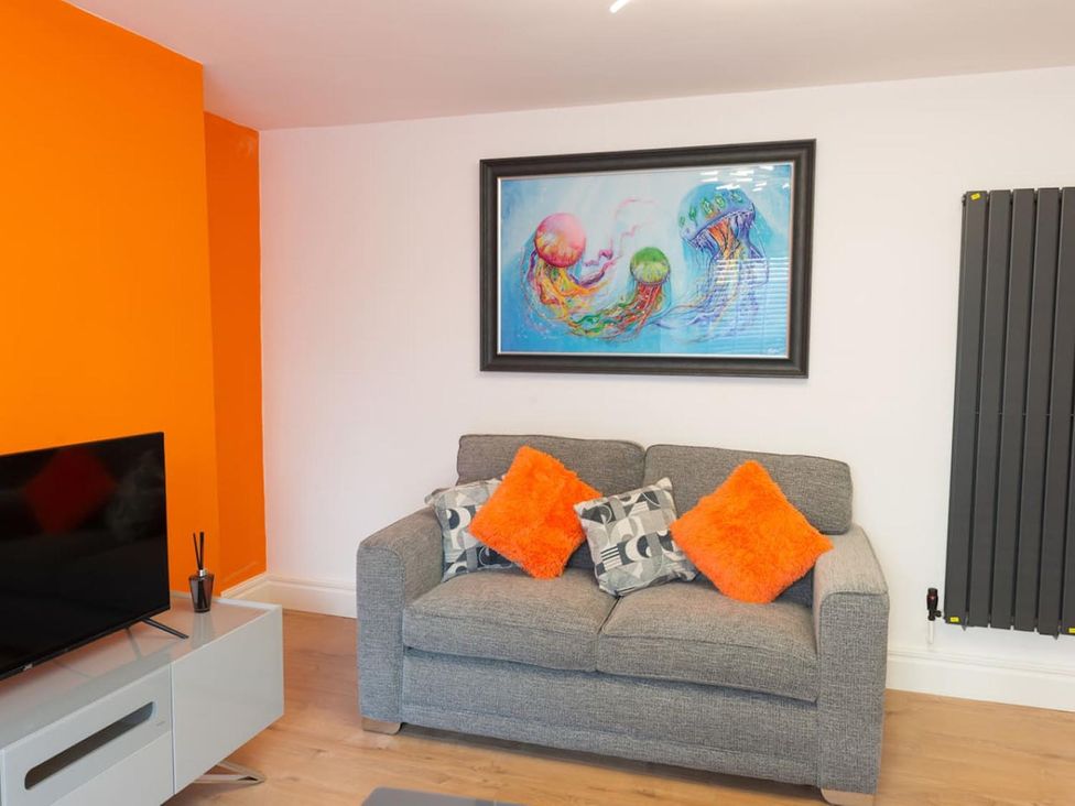A living room with a grey sofa and colorful cushions at The Old Barn in Manchester