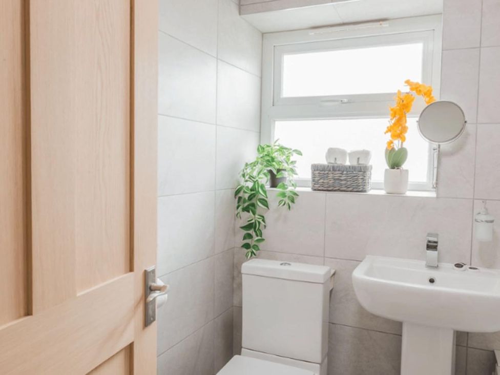 A bathroom featuring a toilet, sink, and window at The Old Barn in Manchester